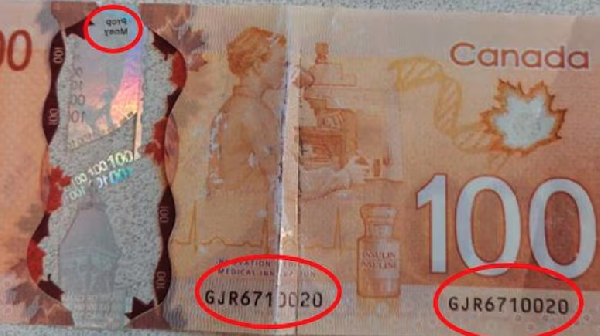 Fake money had the words 'prop money' printed in reverse in small black print on top of the holographic strip on the back of the note.